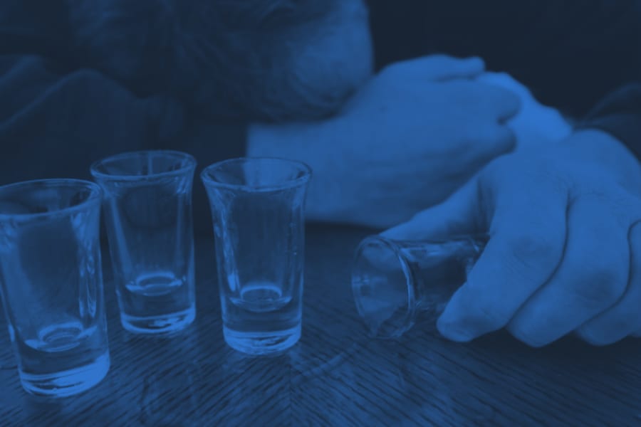 April Alcohol Awareness Month four shot glasses with males head down on table