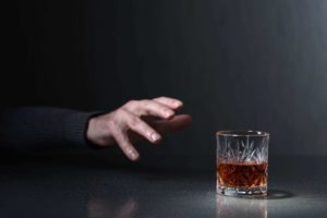 hand reaching for alcohol depicting alcoholism