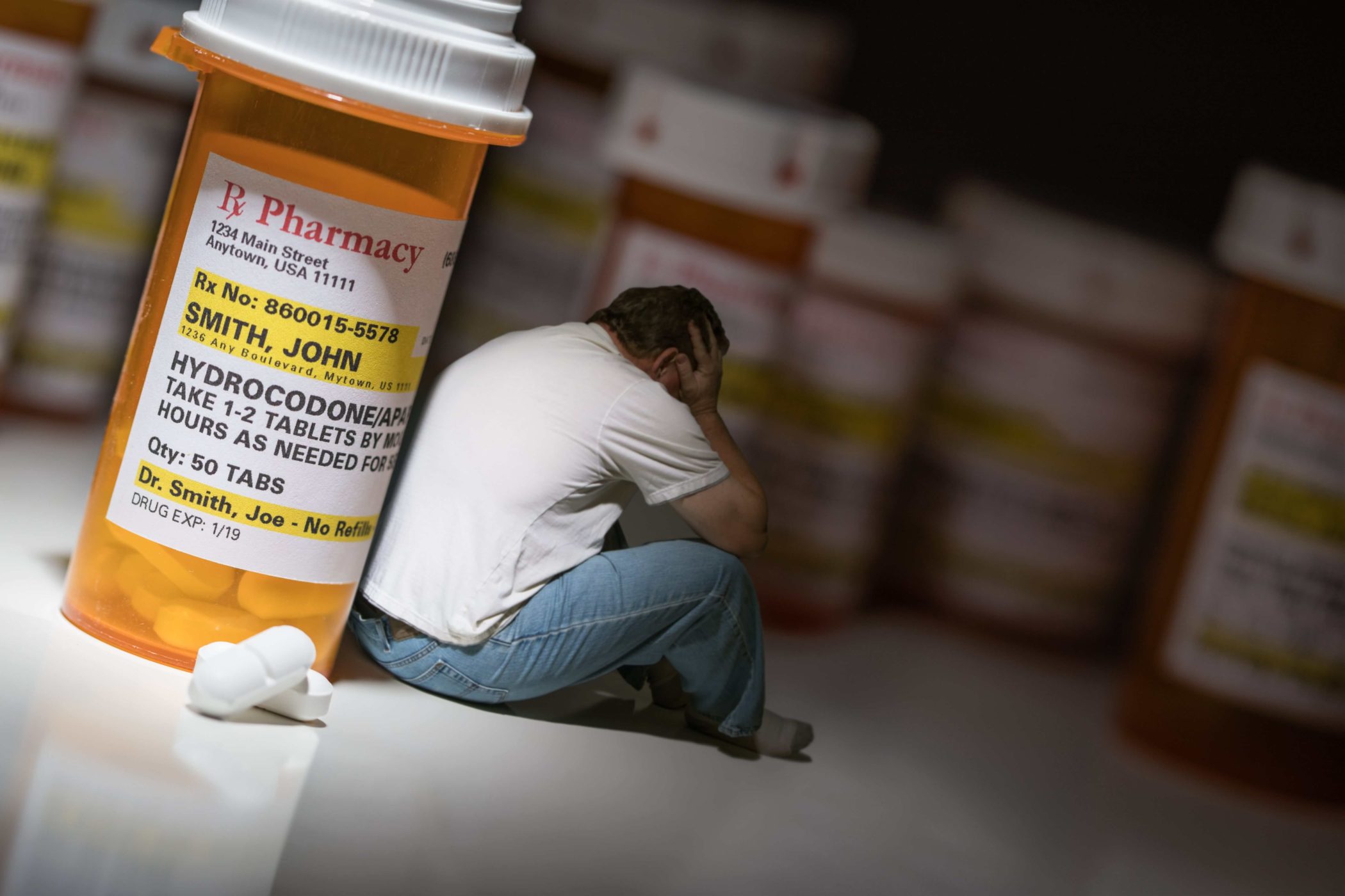 depressed man sitting next to opioids depicting addiction
