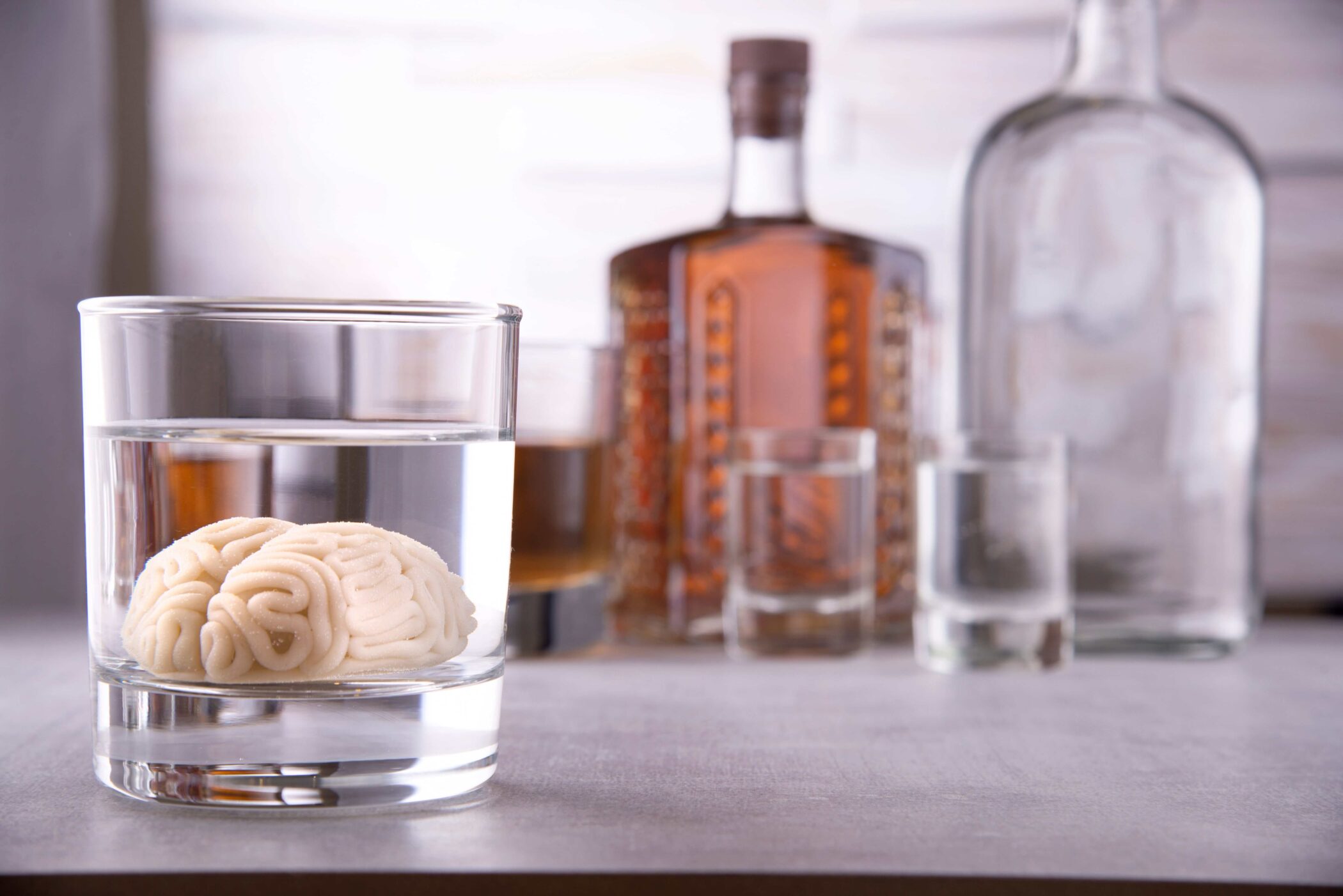 brain in a glass of alcohol next to bottles