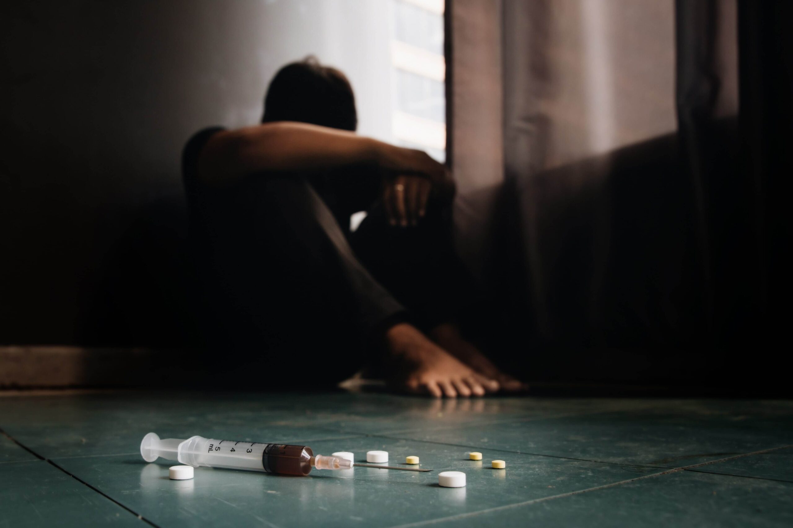 depressed addict sitting in front of drugs