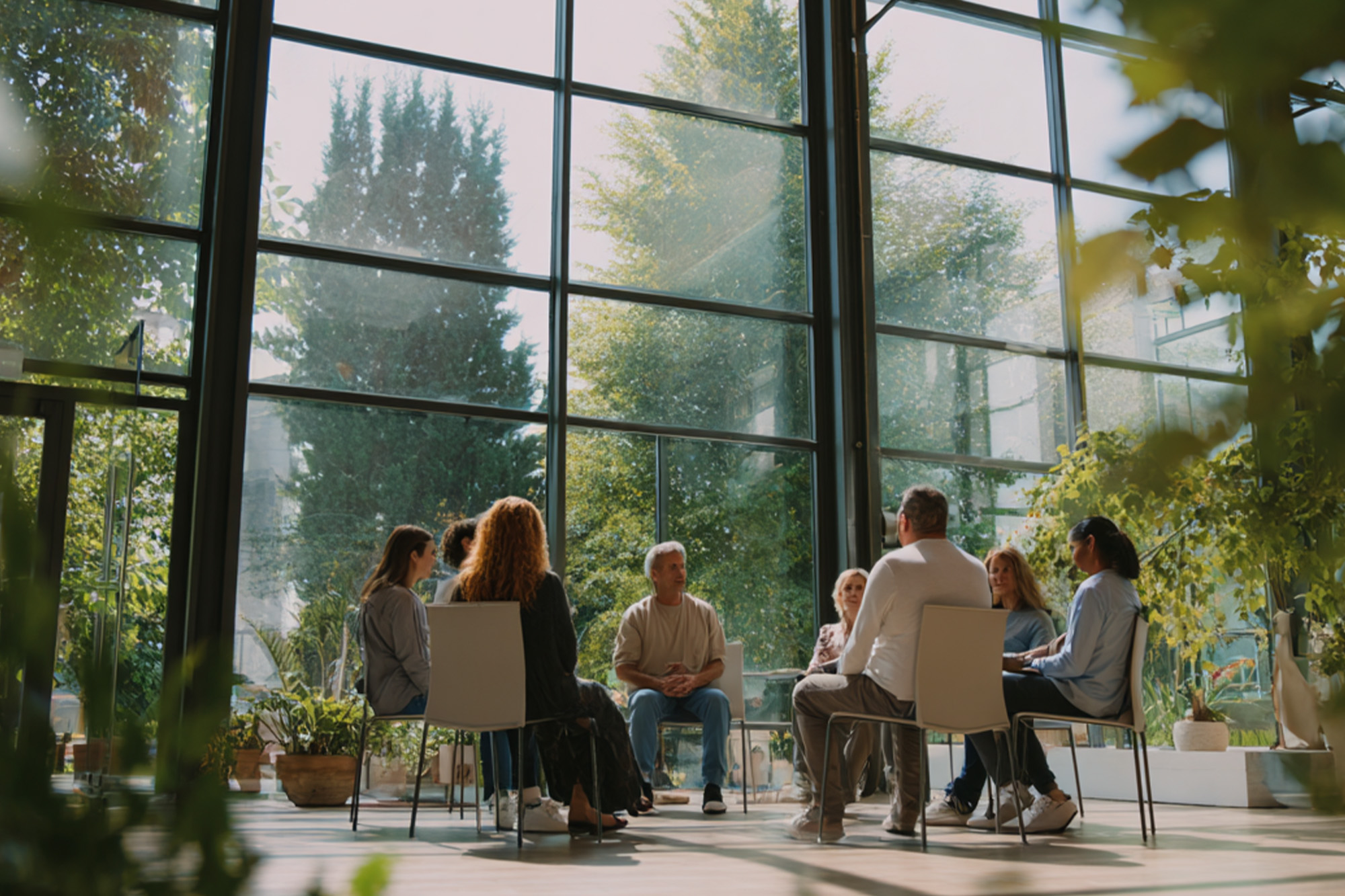 diverse group of people sitting in a therapy circle in a modern counseling center, large windows, green plants