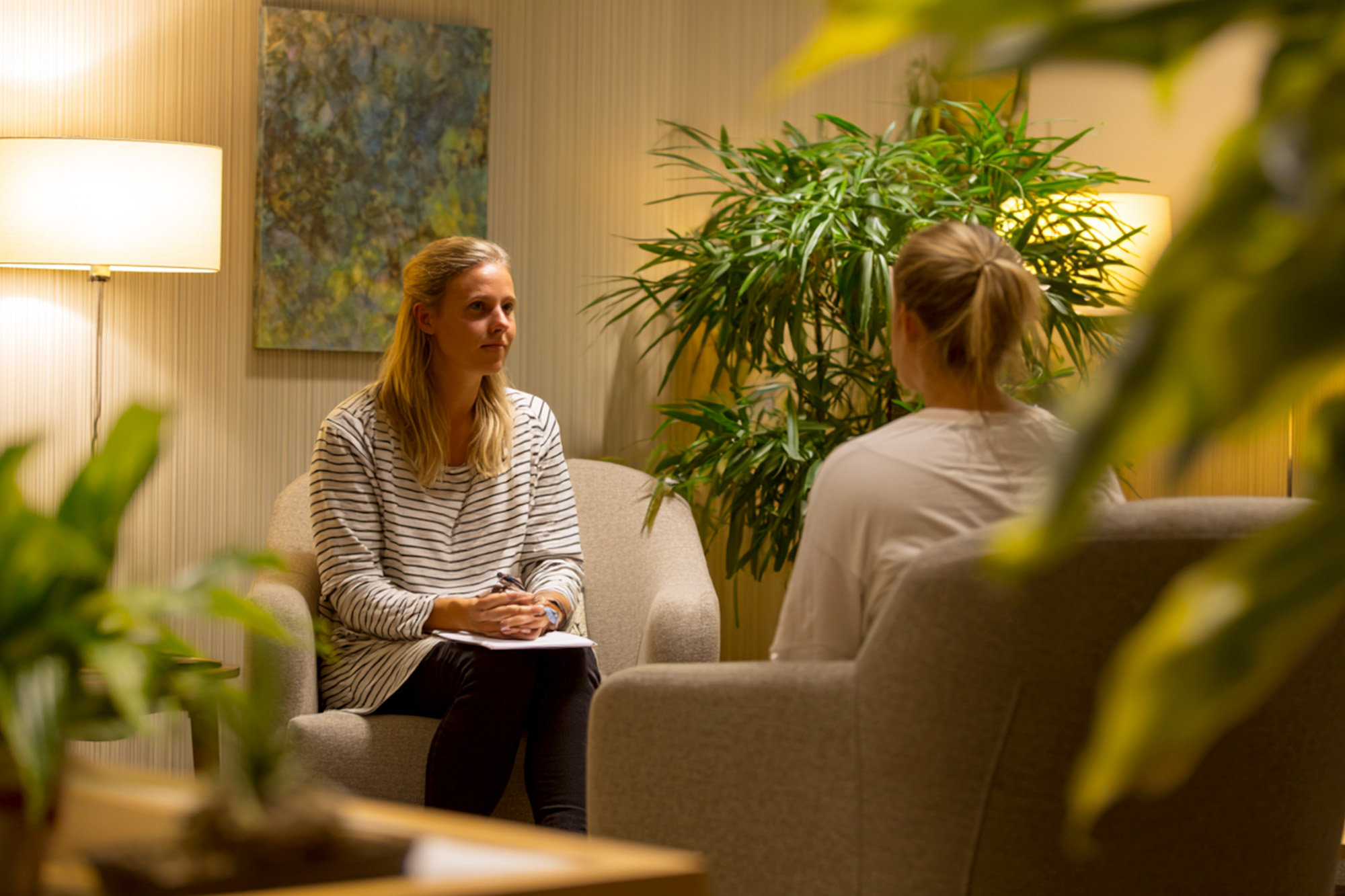 therapy session in a warm softly lit office, therapist listening attentively, comfortable chair therapy session in a warm softly lit office, therapist listening attentively, comfortable chair