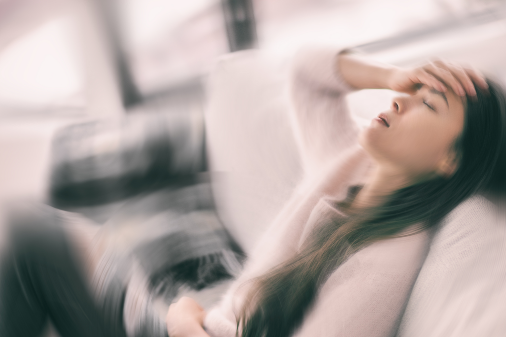 Blurred image of woman experiencing dizziness on a couch, representing seizure risk during alcohol or benzodiazepine detox without medical supervision